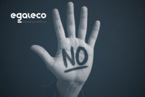 Mano levantada con la palabra “NO” sobre fondo negro, como símbolo de prevención frente al acoso sexual y por razón de sexo.